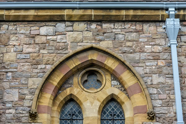 Cast iron gutter and rectangular downpipe beside a Gothic window at St John the Evangelist Church, Taunton, Somerset