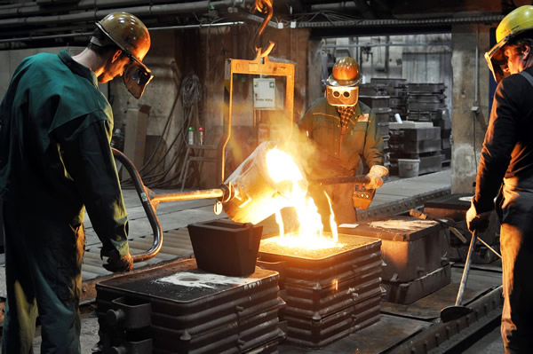 Molten iron being poured into sand moulds in a cast iron foundry
