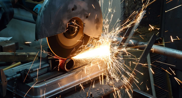 Metal pipe being cut to length with an angle grinder, sparks flying