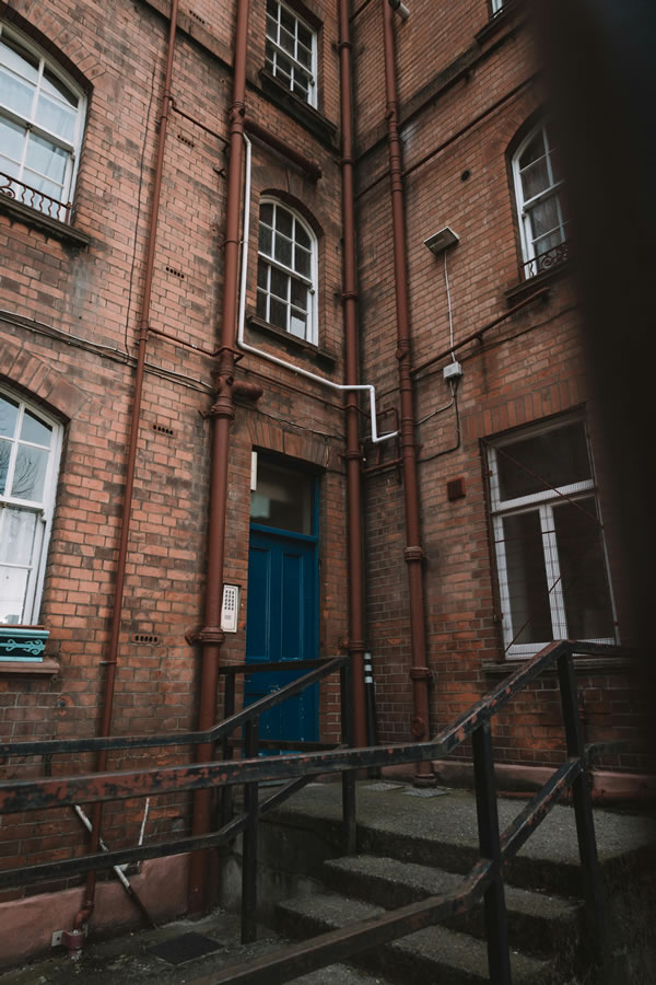 Listed red brick industrial building with cast iron downpipes and a blue panelled door
