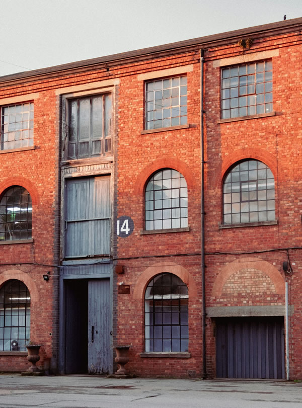 Red brick industrial building with tall arched windows and loading doors