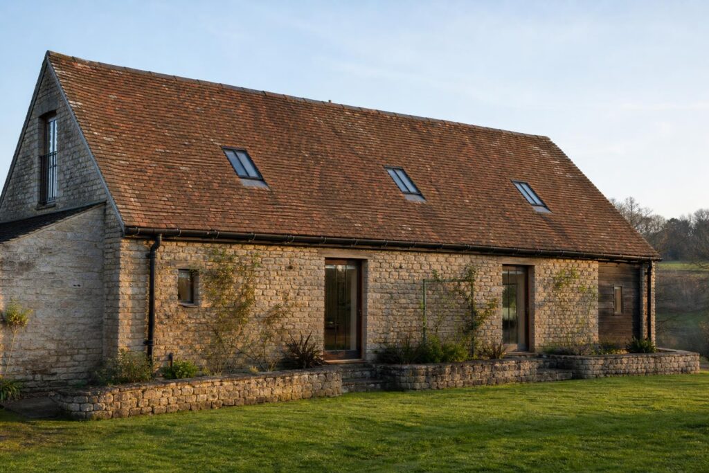 Converted stone barn with three flush conservation rooflights on the rear slope and black cast iron half-round gutters