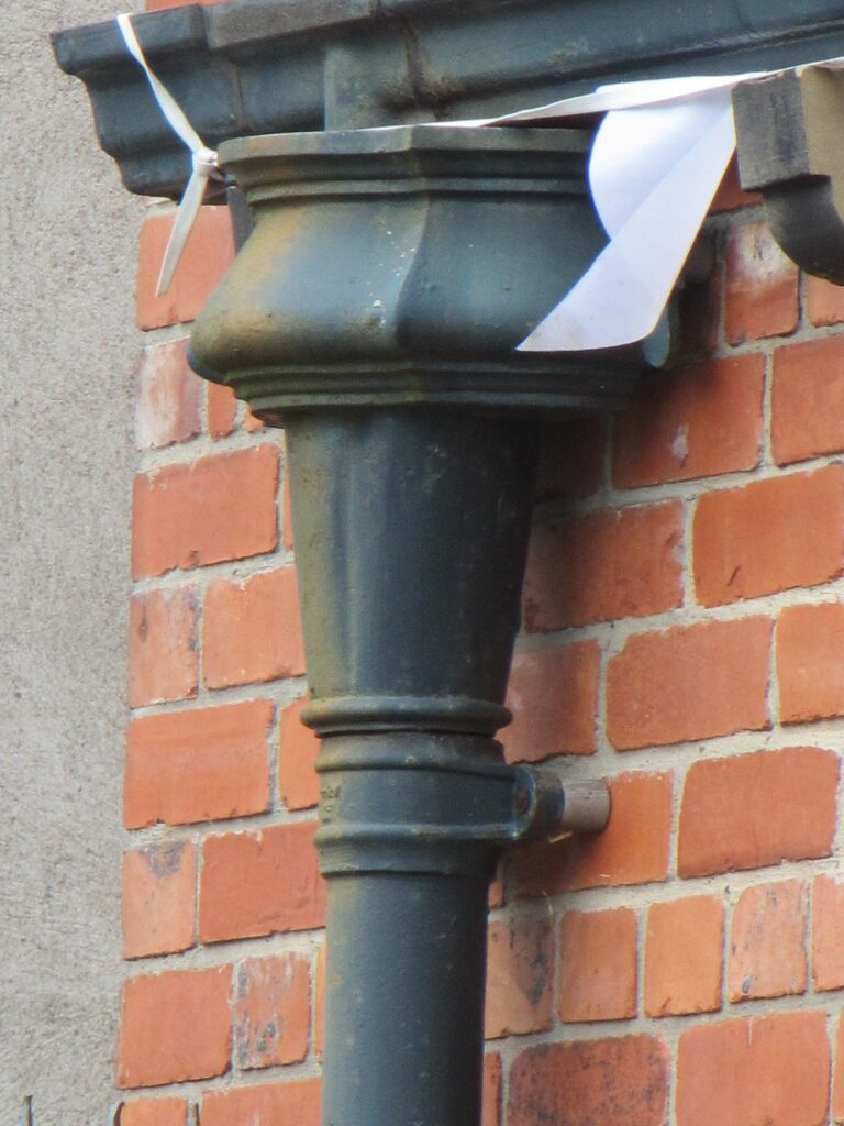 Cast iron downpipe and hopper detail against red brick
