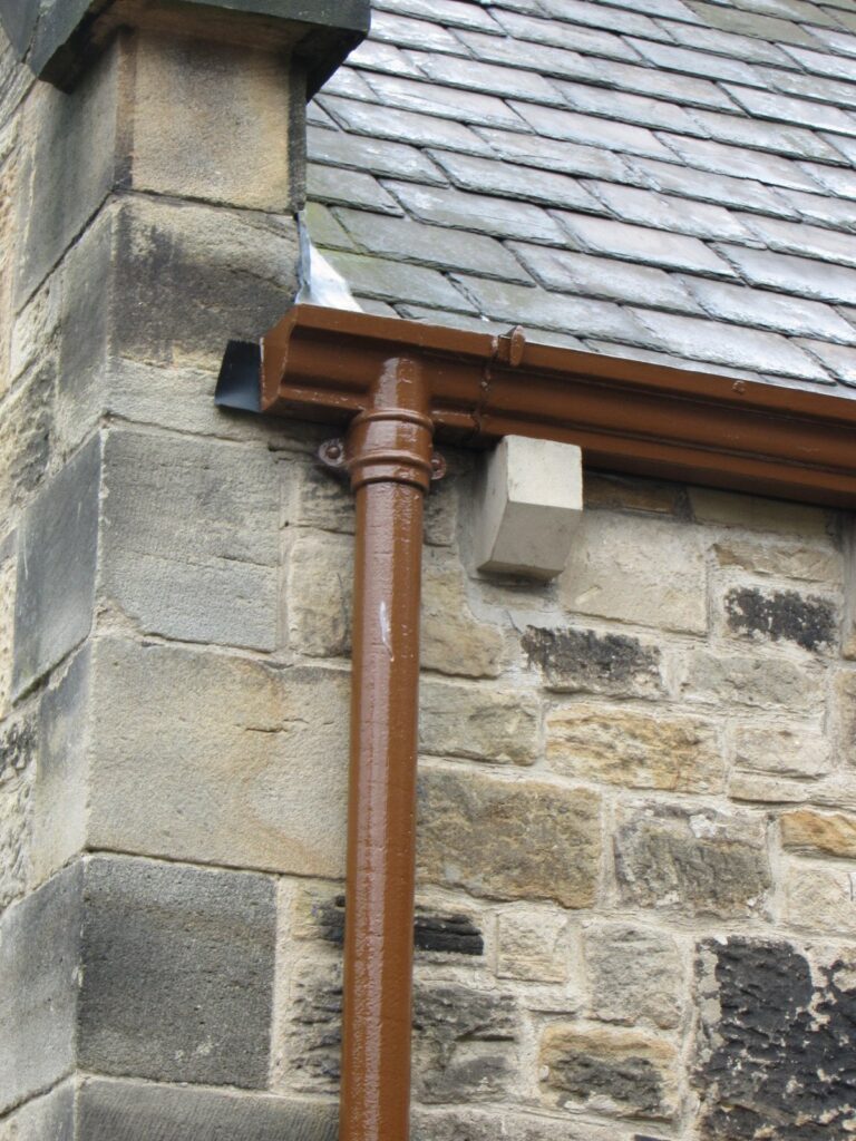 Cast iron downpipe on a moulded stone corbel, brown painted finish