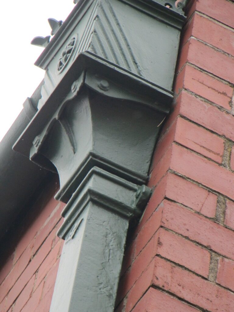 Ornate cast iron gutter bracket in a green painted finish
