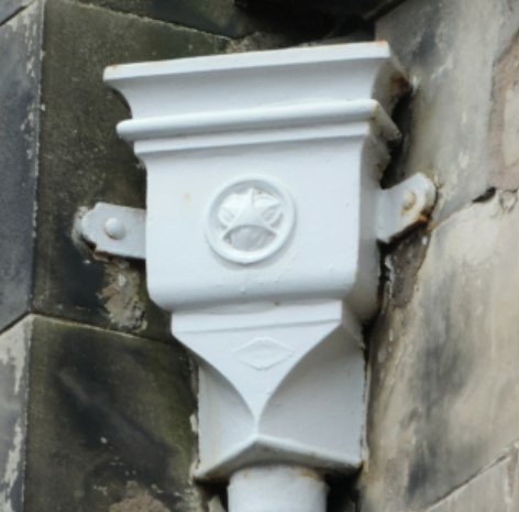 Painted cast iron corner hopper head with a cast rosette motif