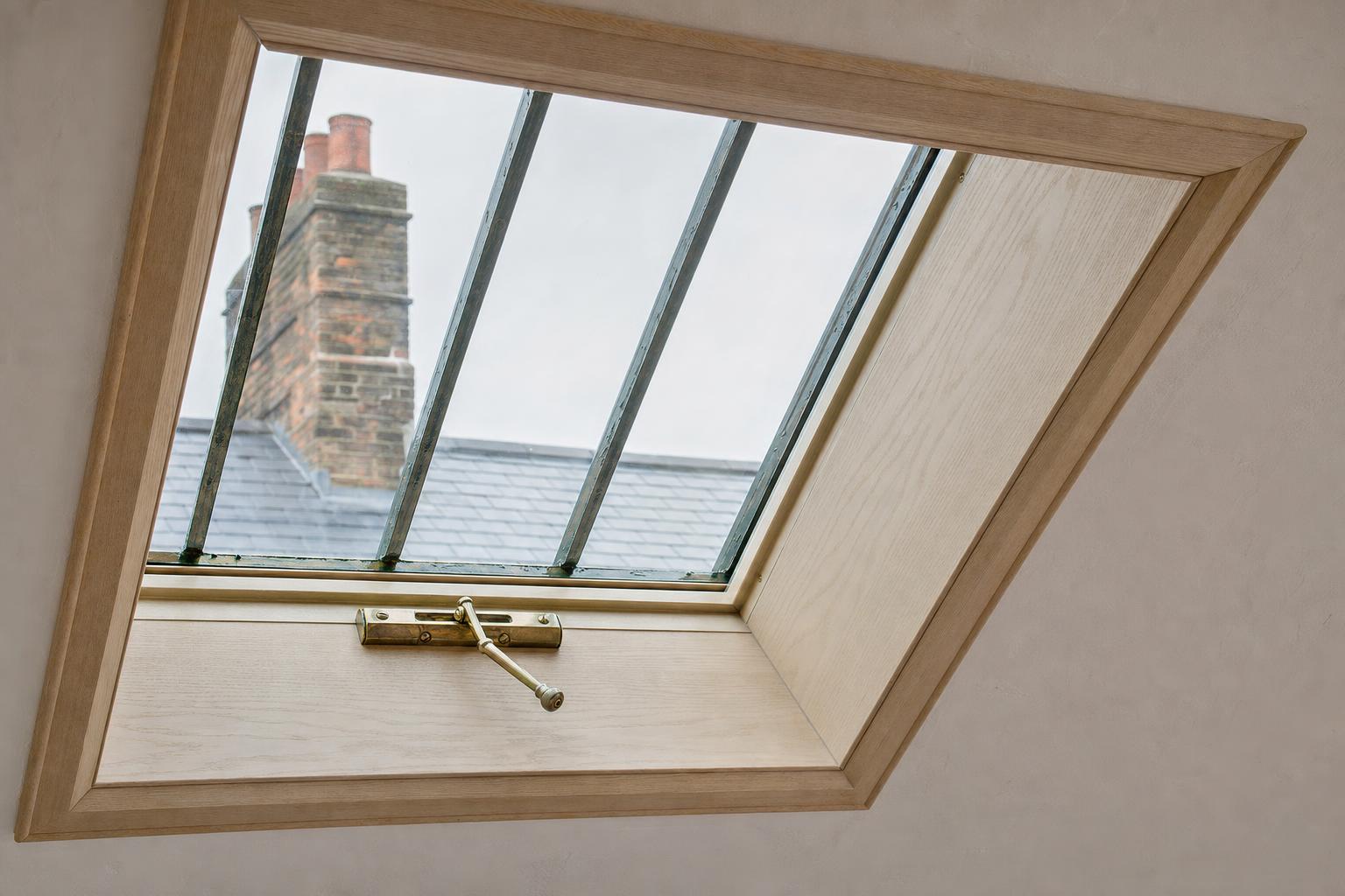 The interior of a conservation rooflight with a pale ash timber lining and a brass stay.