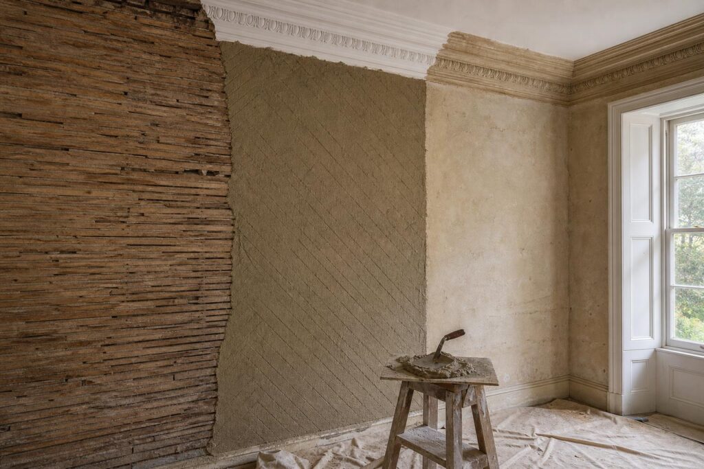 Georgian room mid-repair: riven oak laths, haired lime scratch coat, and a run cornice with a new section beside the original