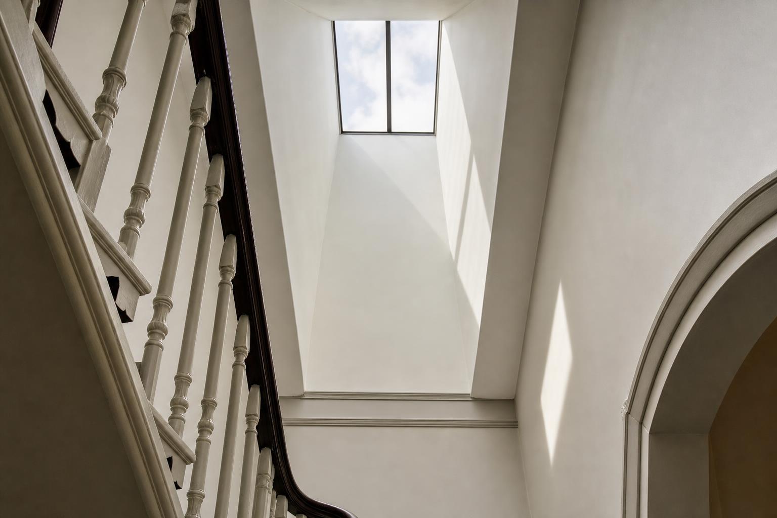 White splayed light well carrying daylight from a single conservation rooflight down into a Georgian stair well