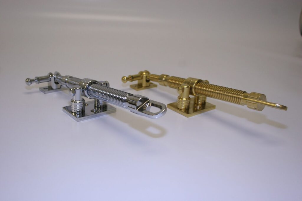 Polished chrome and polished brass screw-jack rooflight winders with eye ends for a pole, side by side