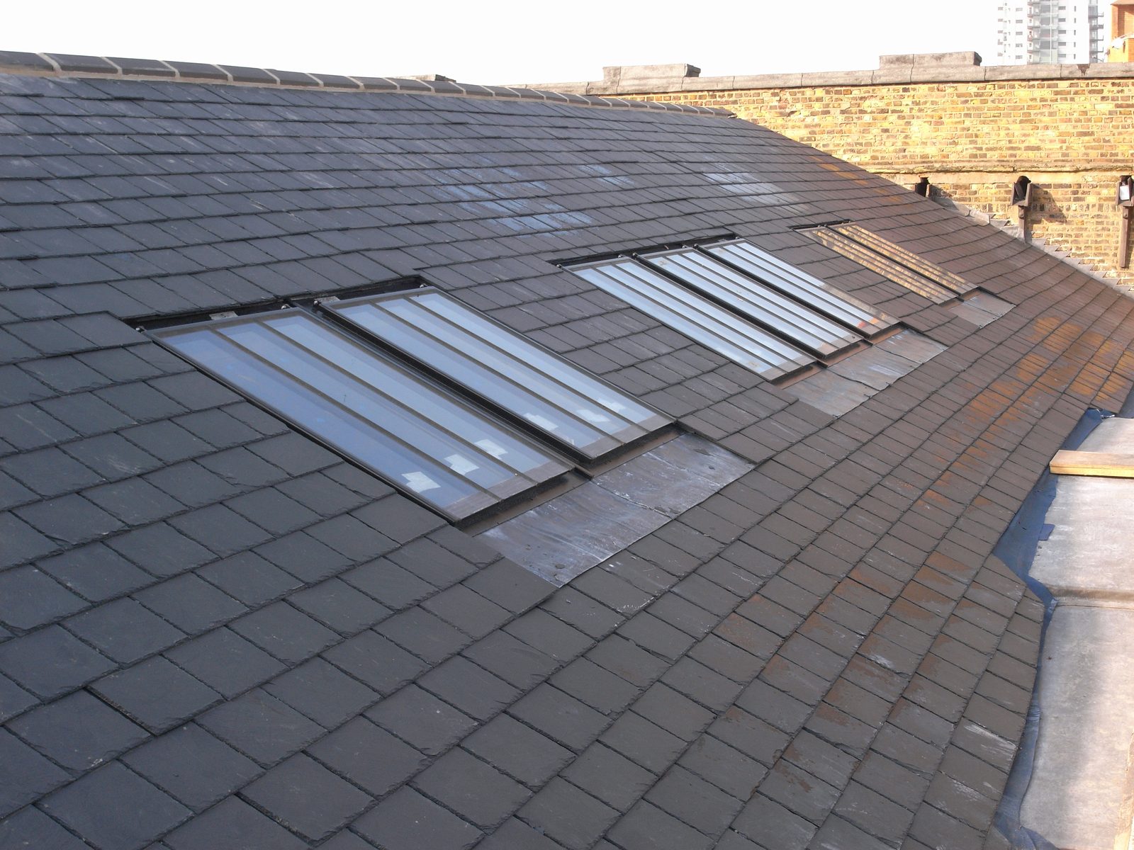 Newly installed conservation rooflights in a slate roof, with lead aprons and side flashings dressed around each frame