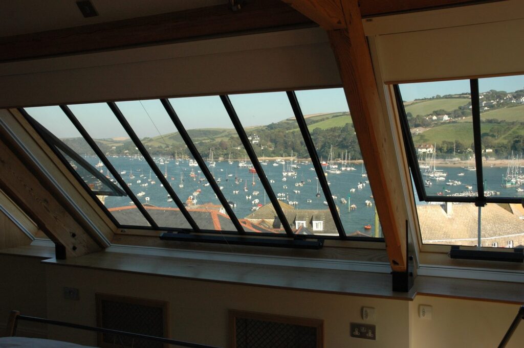 Interior of a timber-framed room with a long run of conservation rooflights and glazing bars looking out over a harbour