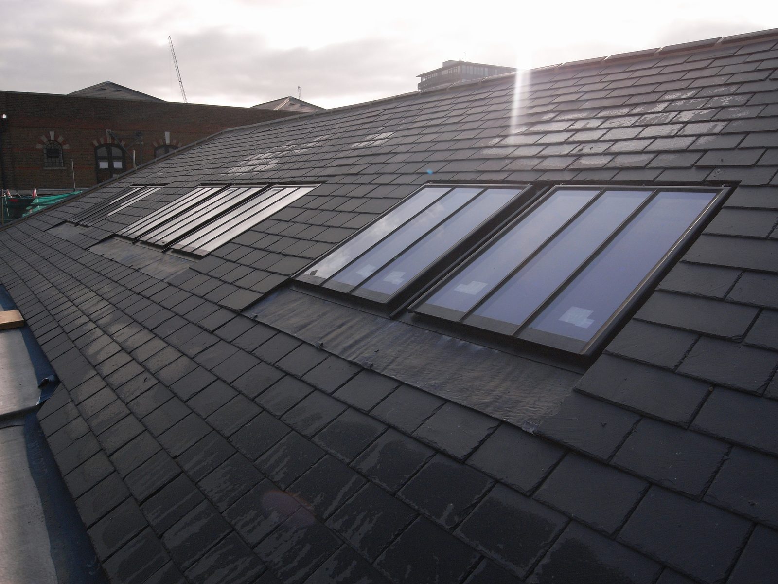 Two runs of linked conservation rooflights set flush into a natural slate roof on a London warehouse conversion