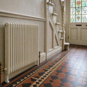 Slim Edwardian two-column cast iron radiator against the wall of a narrow Edwardian hallway with a tiled floor.