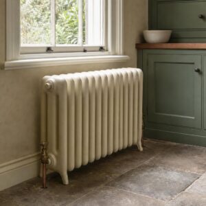 Deep Edwardian six-column cast iron radiator in cream under a window in a period house kitchen.