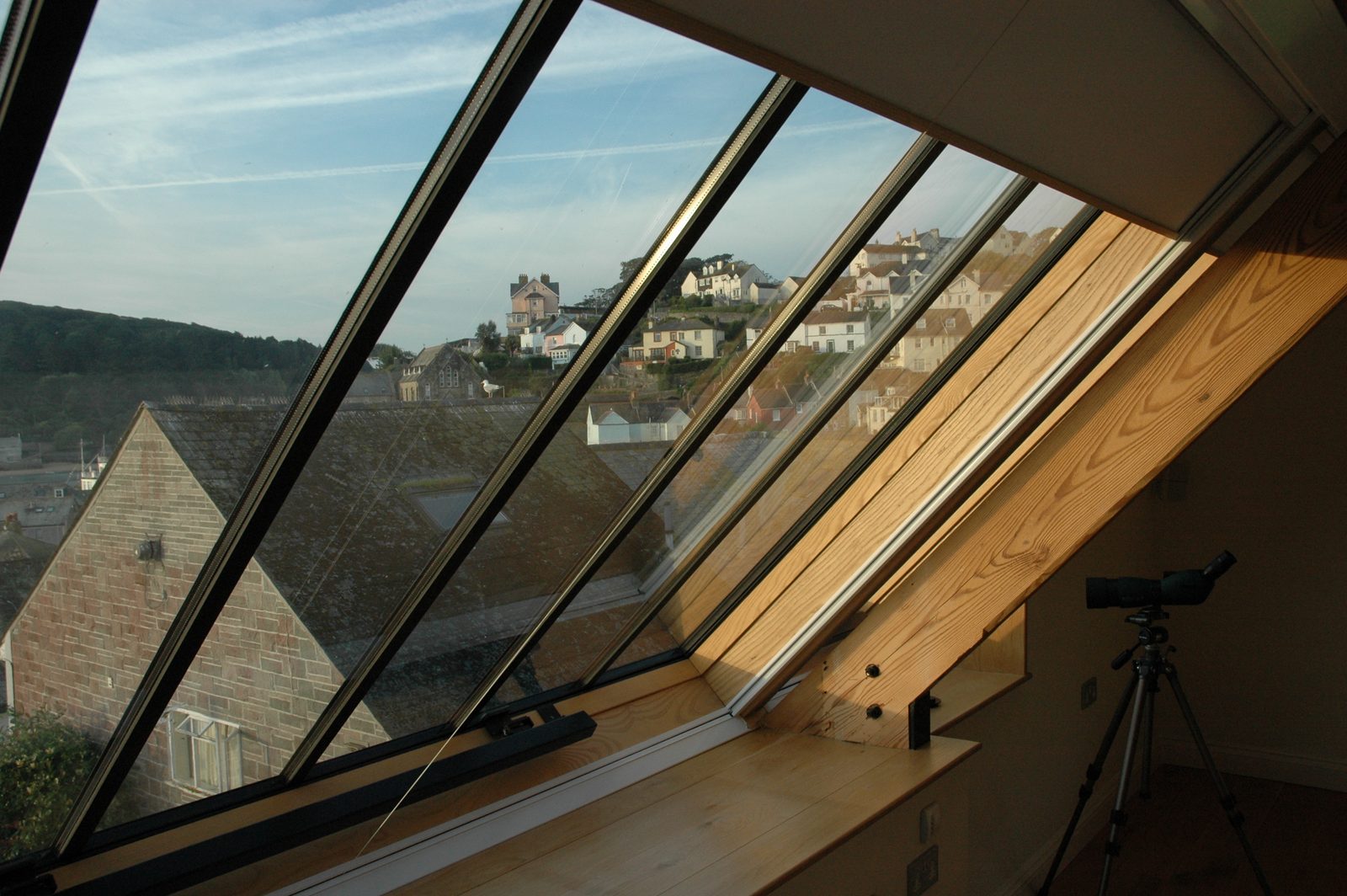 Large run of linked conservation rooflights in a pitched roof, seen from inside a coastal house with rooftops beyond