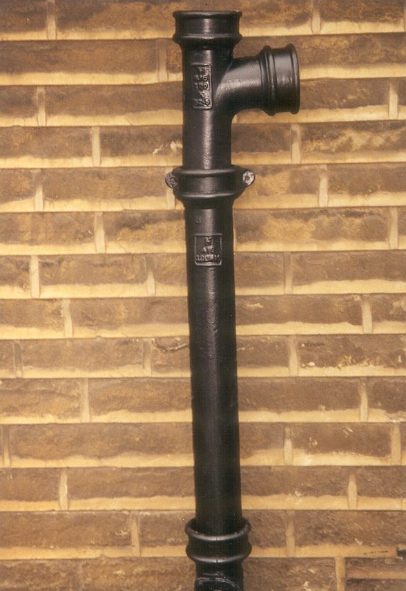 LCC cast iron soil pipe with a branch fitting and eared sockets on a brick wall