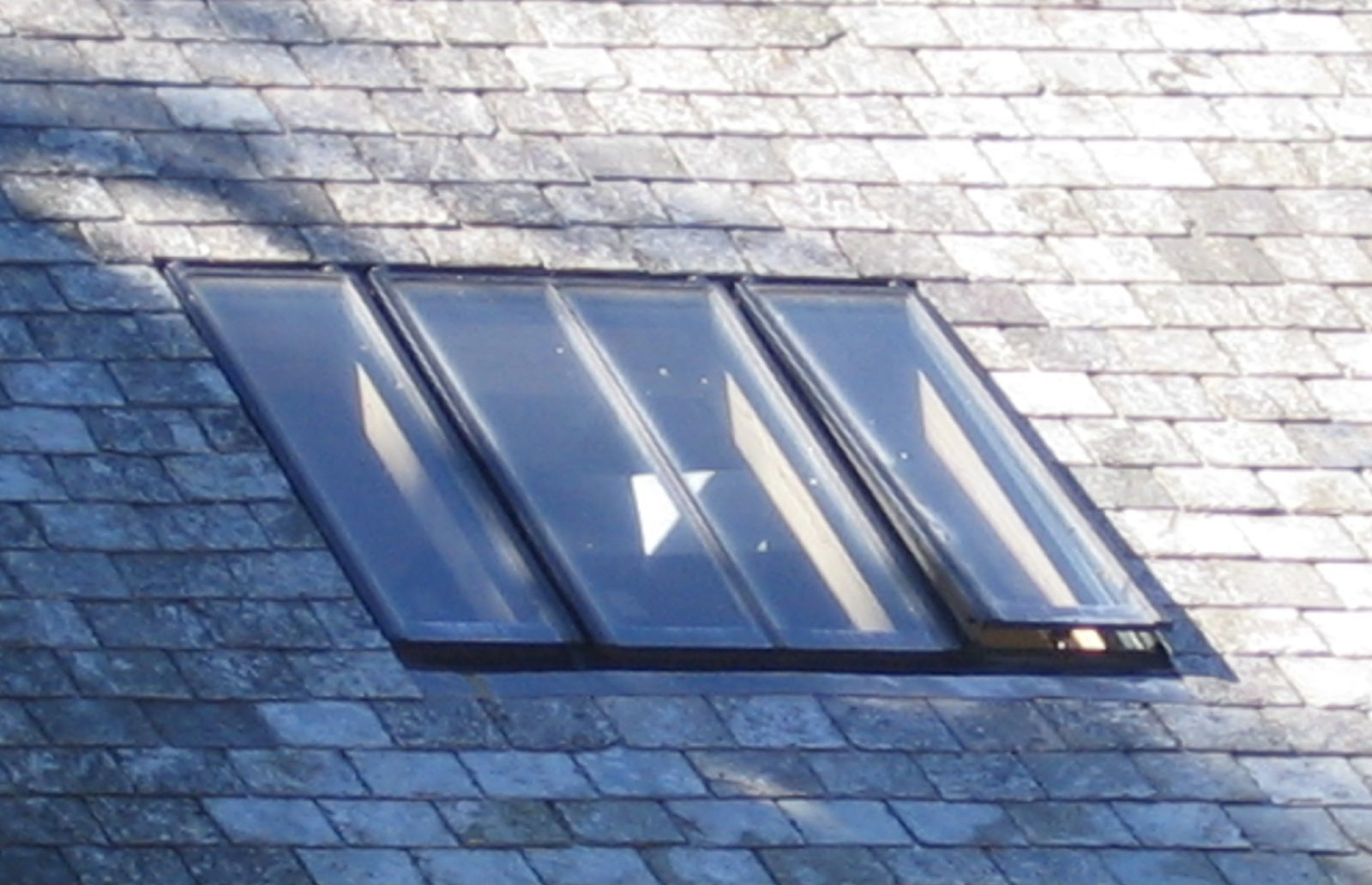 Three-bay linked conservation rooflight with slim glazing bars, fitted flush in a Devon slate roof with one sash open