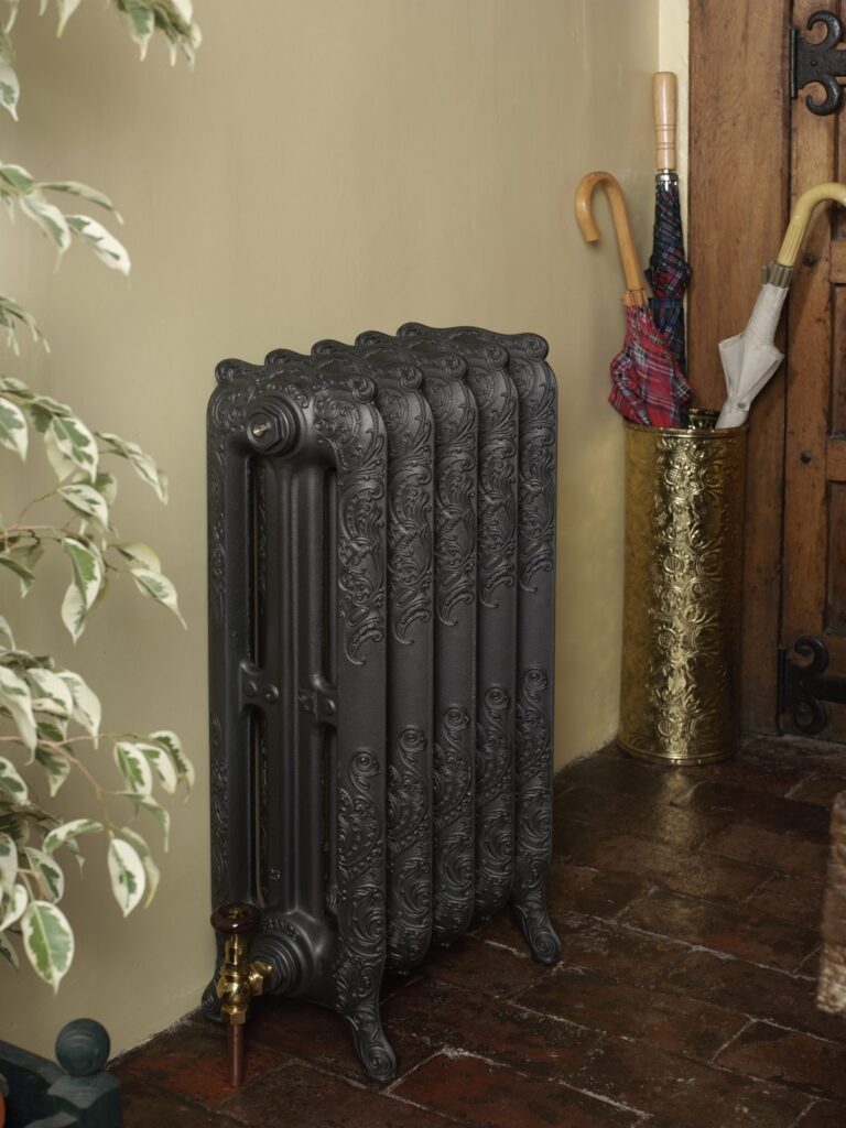 Ornate Nouveau cast iron radiator in a period hallway with a tiled floor