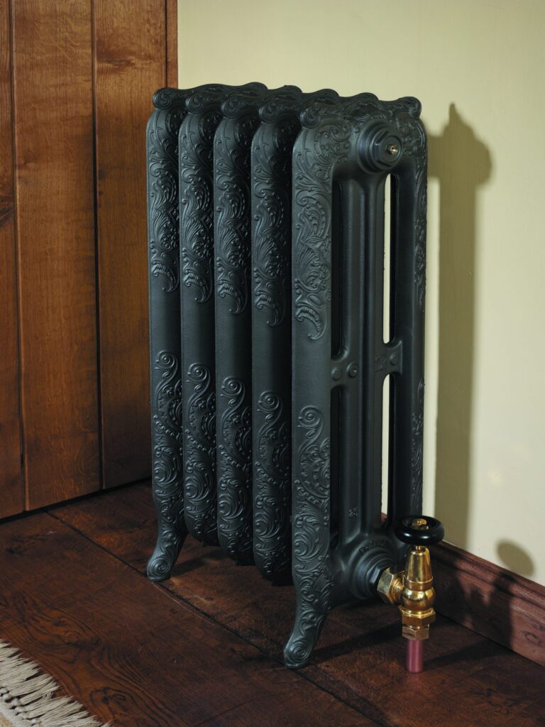 Nouveau cast iron radiator with a brass valve against timber panelling
