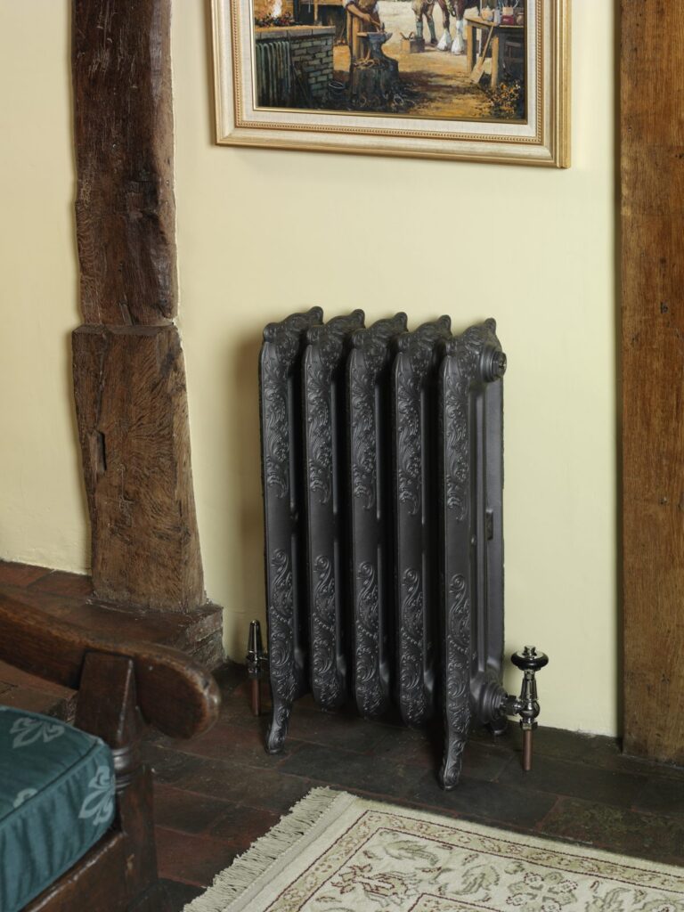 Nouveau cast iron radiator in a period living room beside a timber post