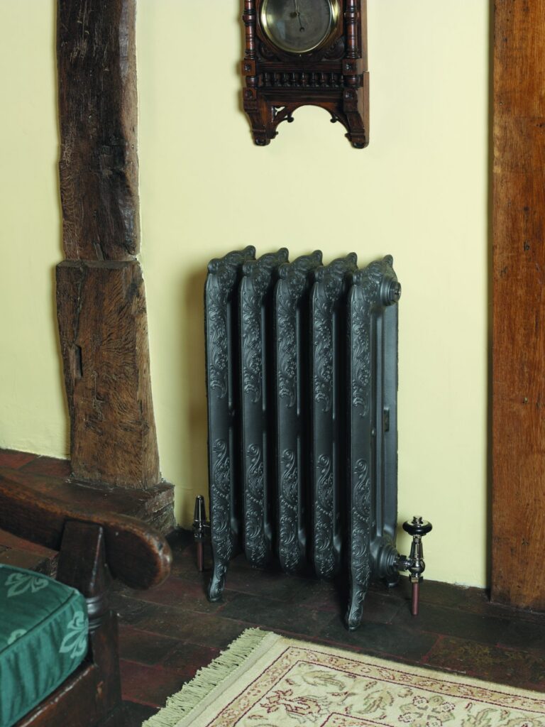 Nouveau cast iron radiator below a barometer in a period hall