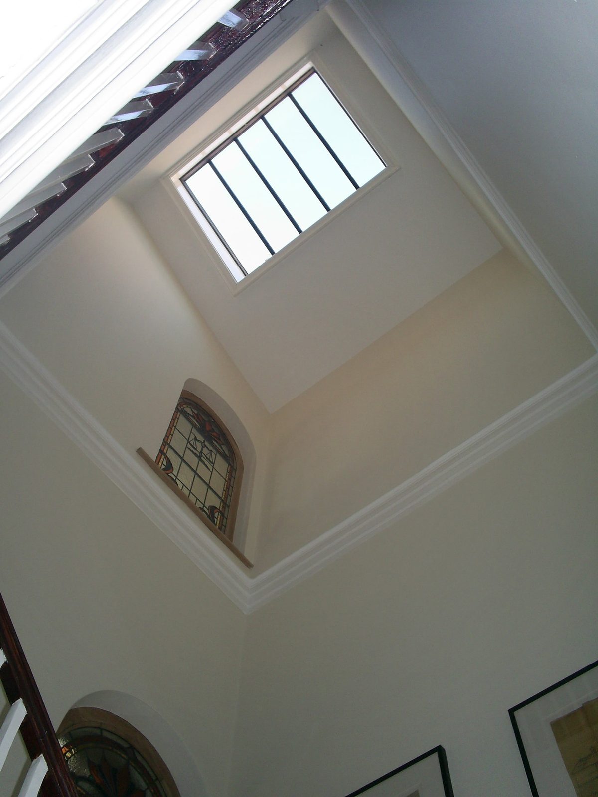 Conservation rooflight at the top of a deep painted light well, lighting a stairwell with an arched window below