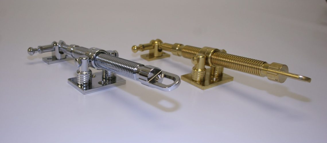 Polished chrome and polished brass screw-jack rooflight winders with eye ends for a pole, side by side