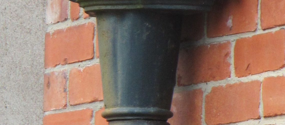 Cast iron downpipe and hopper detail against red brick